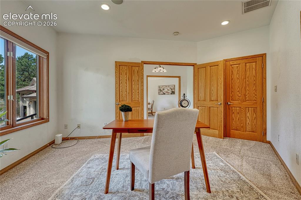 Image 15 of 50: Double doors lead into the main level office with closet, recessed lighting