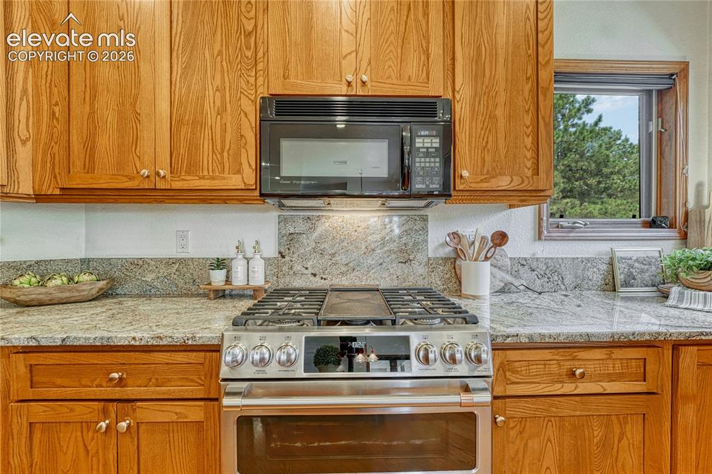 Image 21 of 50: Double oven gas range with granite backsplash.