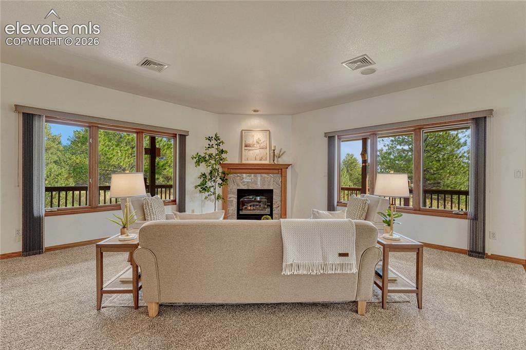 Image 3 of 50: Great room with gas fireplace, neutral carpet, and in-ceiling speakers.