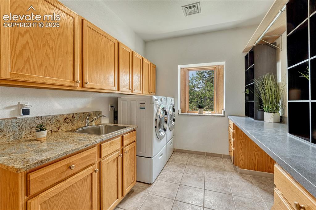 Image 31 of 50: Main level laundry with granite counters, utility sink and a window. Washer
