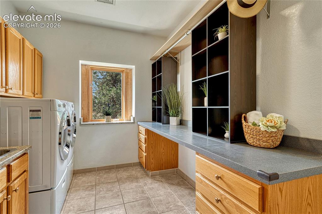 Image 32 of 50: Laundry has built-in cabinets and a long folding counter.