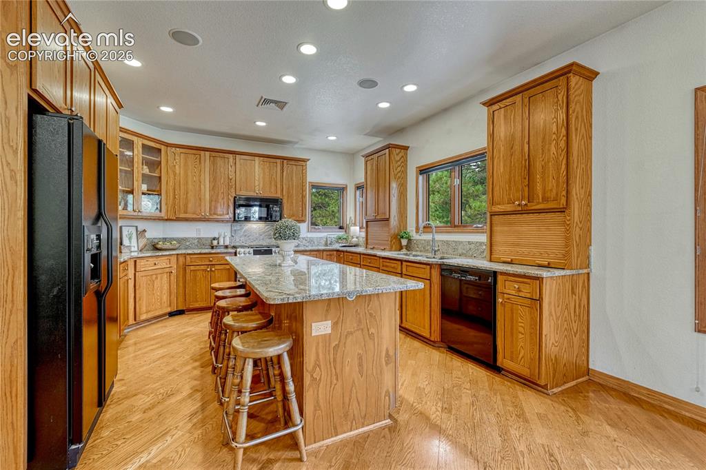 Image 4 of 50: Kitchen with plentiful cabinets, granite counters and hardwood flooring.