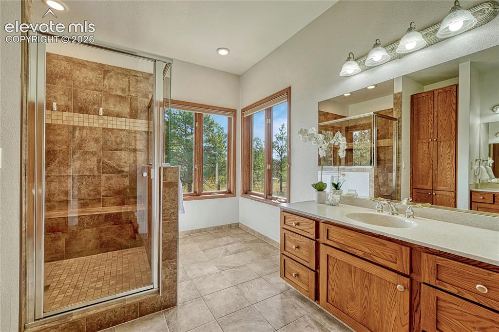 Image 6 of 50: Primary bath with tile flooring two separate sink vanities, and a large wal