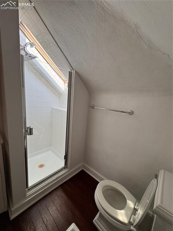 Image 12 of 16: Bathroom with a shower stall, vaulted ceiling, wood-type flooring, and a te