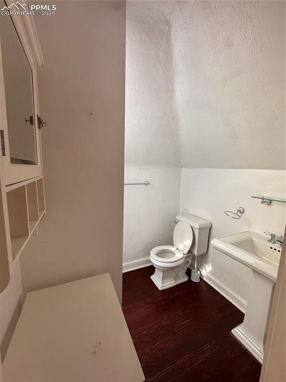 Image 13 of 16: Half bathroom with a textured ceiling, wood finished floors, and lofted cei
