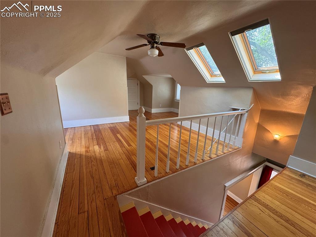 Image 15 of 16: Staircase featuring hardwood / wood-style flooring, lofted ceiling, a skyli