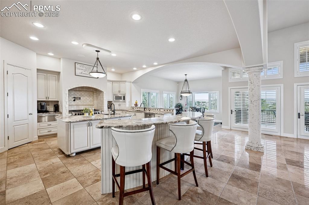 Image 13 of 48: Kitchen with a large island, stainless steel microwave, decorative columns,