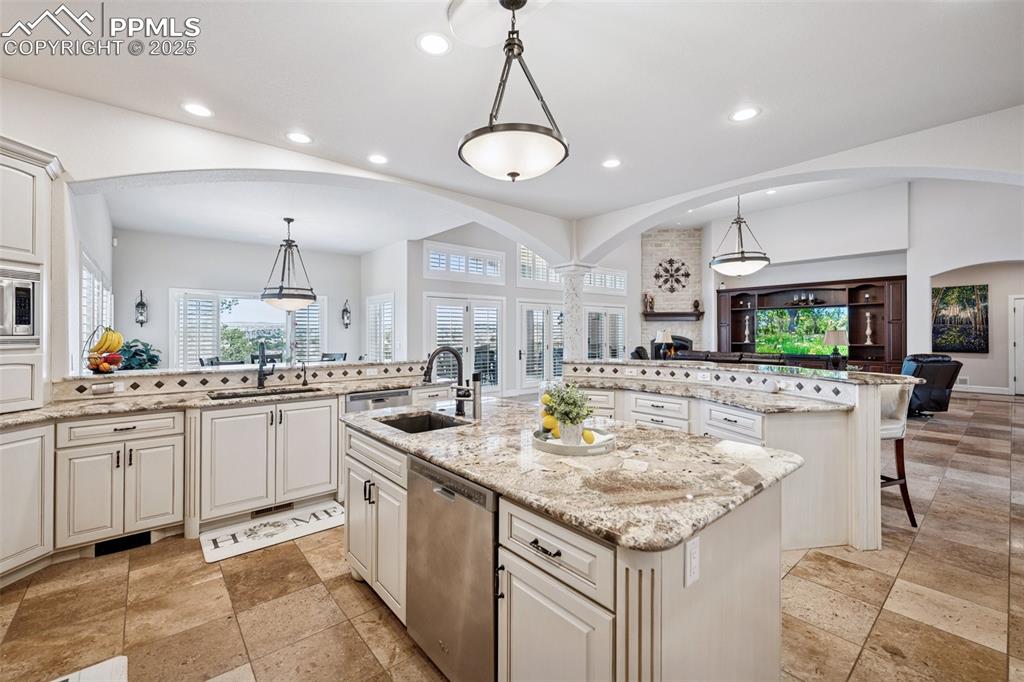 Image 17 of 48: Kitchen featuring arched walkways, a kitchen island with sink, appliances w