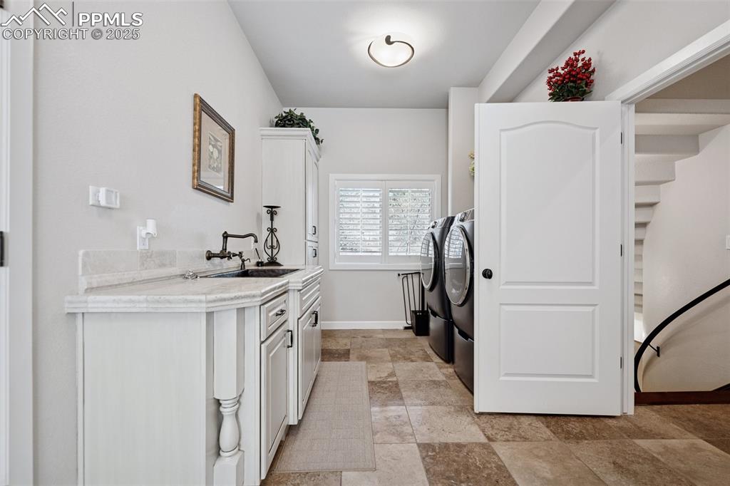 Image 26 of 48: Clothes washing area featuring a sink, stone finish flooring, washing machi
