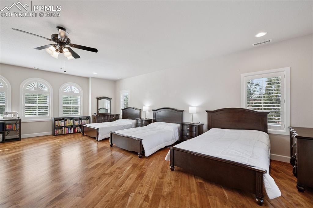 Image 28 of 48: Bedroom with wood finished floors, multiple windows, and visible vents