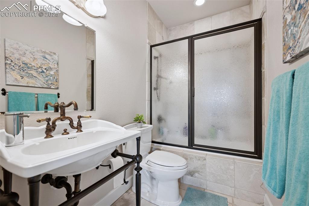Image 29 of 48: Full bathroom with tiled shower / bath combo, toilet, a sink, and tile patt