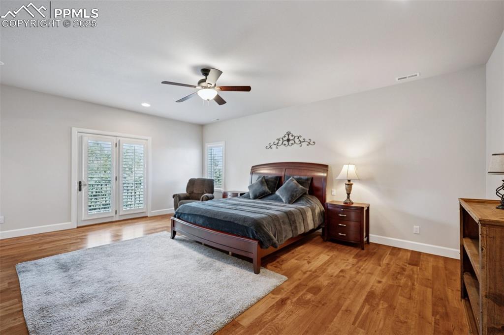 Image 30 of 48: Bedroom with wood finished floors, visible vents, baseboards, and access to