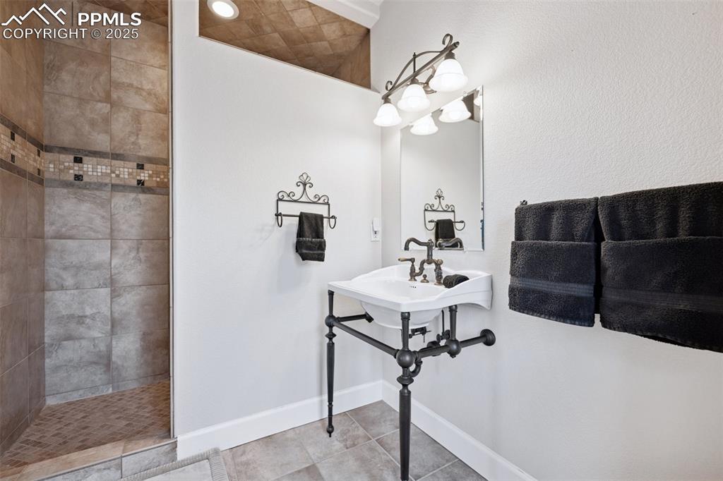 Image 31 of 48: Bathroom with baseboards, tile patterned flooring, and a walk in shower