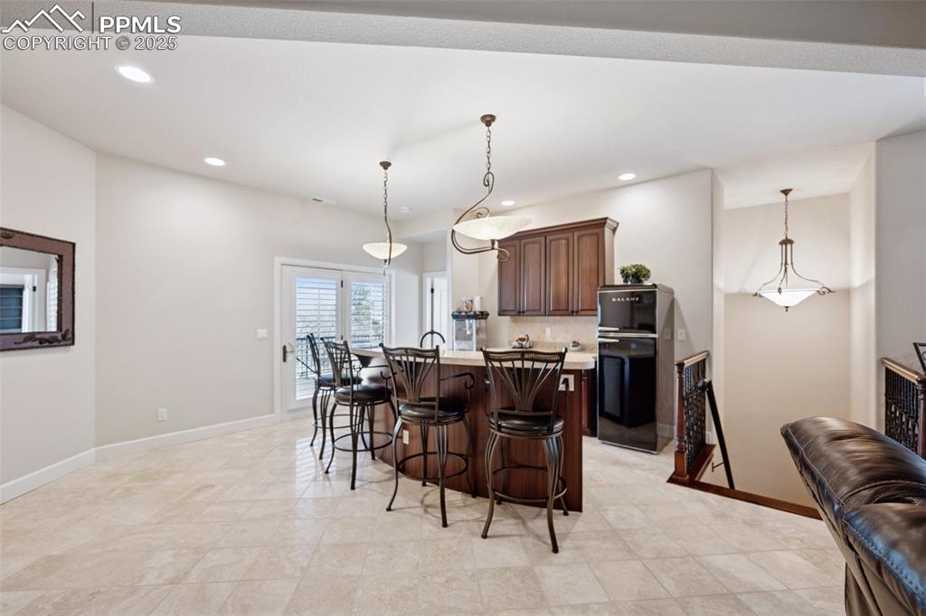 Image 37 of 48: Kitchen featuring a breakfast bar area, a center island with sink, light co