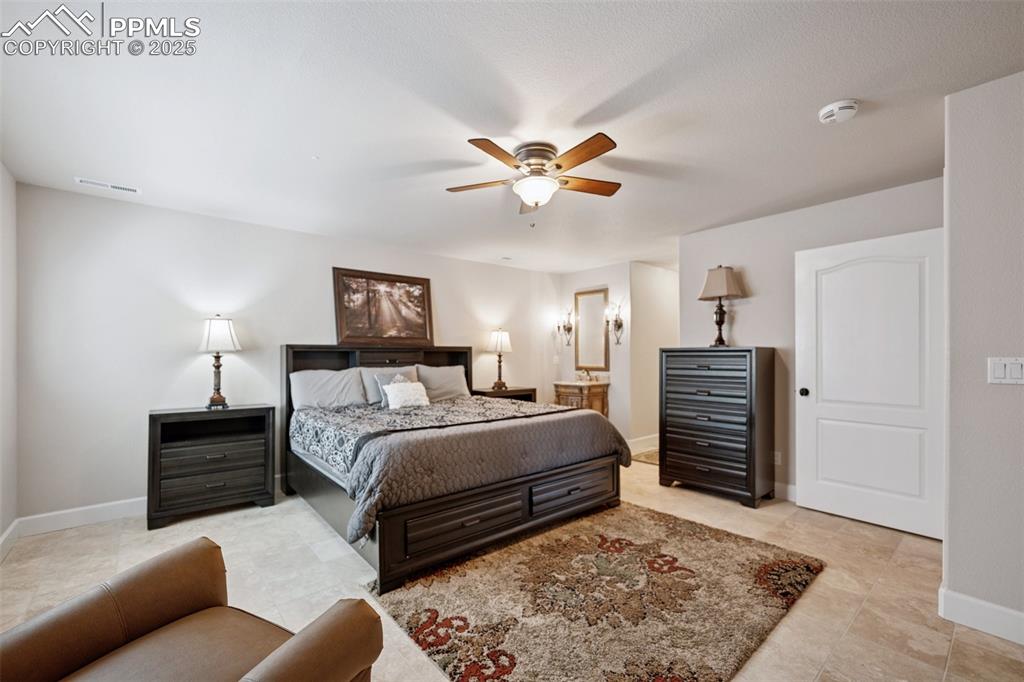 Image 39 of 48: Bedroom with ceiling fan, baseboards, ensuite bathroom, and visible vents