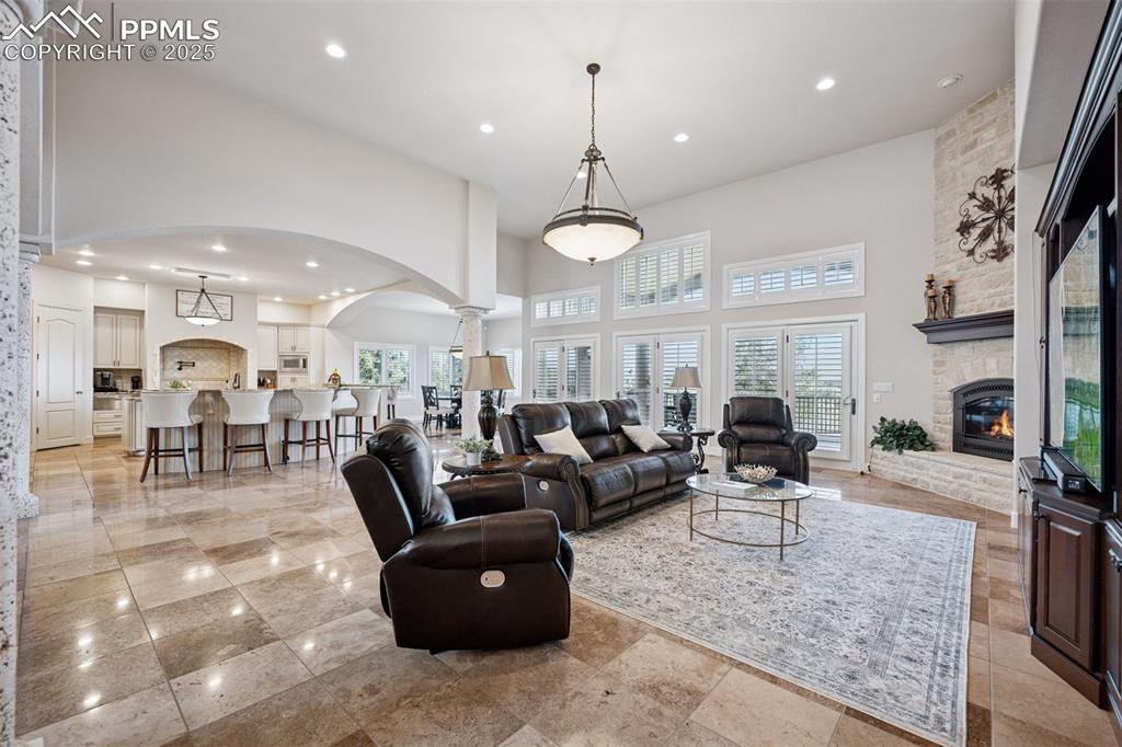 Image 8 of 48: Living area featuring a fireplace, arched walkways, a towering ceiling, and
