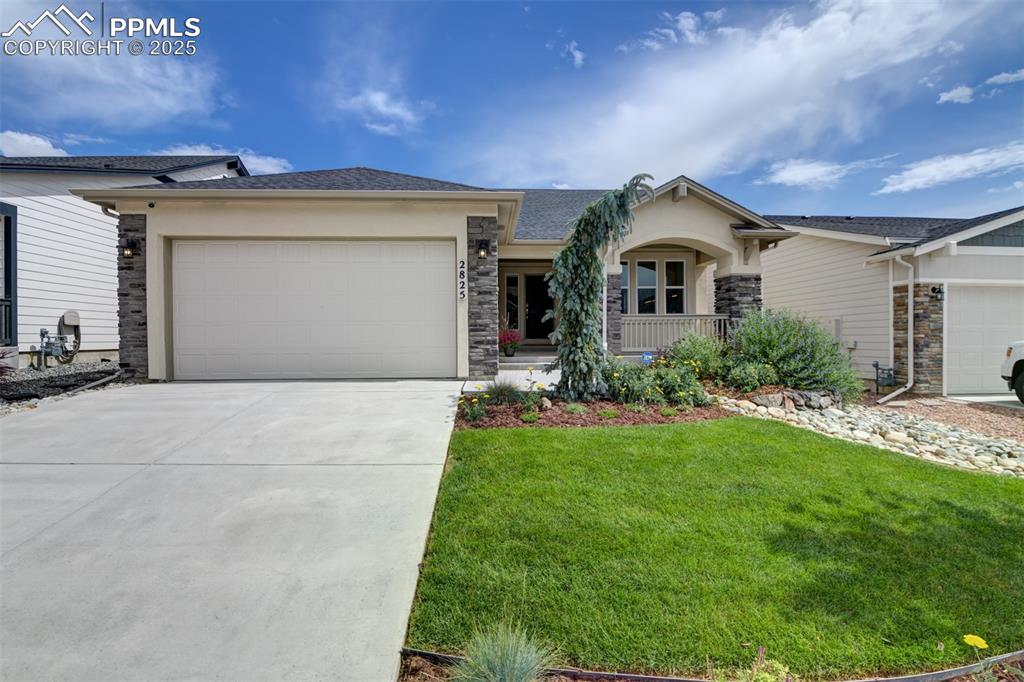 Image 2 of 44: View of front facade with stone siding, a garage, a porch, concrete drivewa