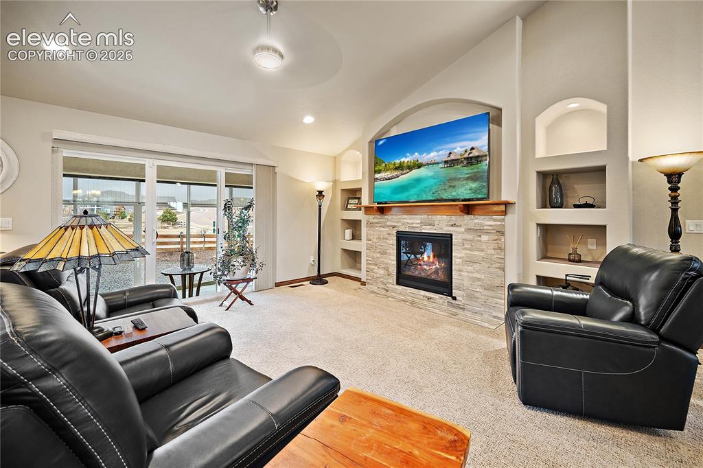 Image 6 of 44: Living room with gas fireplace, stone surround and custom built-ins. Walk o