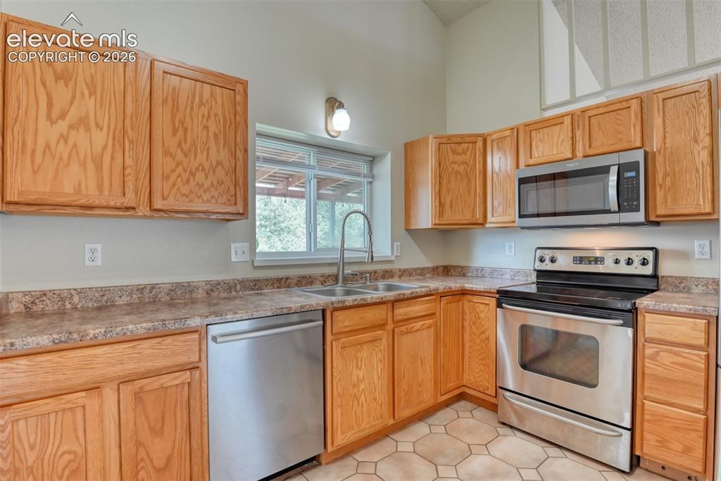 Image 10 of 50: U-shaped kitchen featuring light wood cabinetry, stainless steel appliances