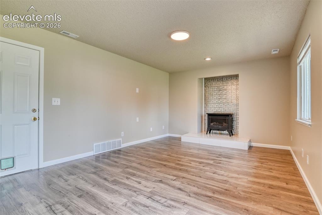 Image 14 of 50: Spacious lower level family room featuring wood-finish flooring, a decorati