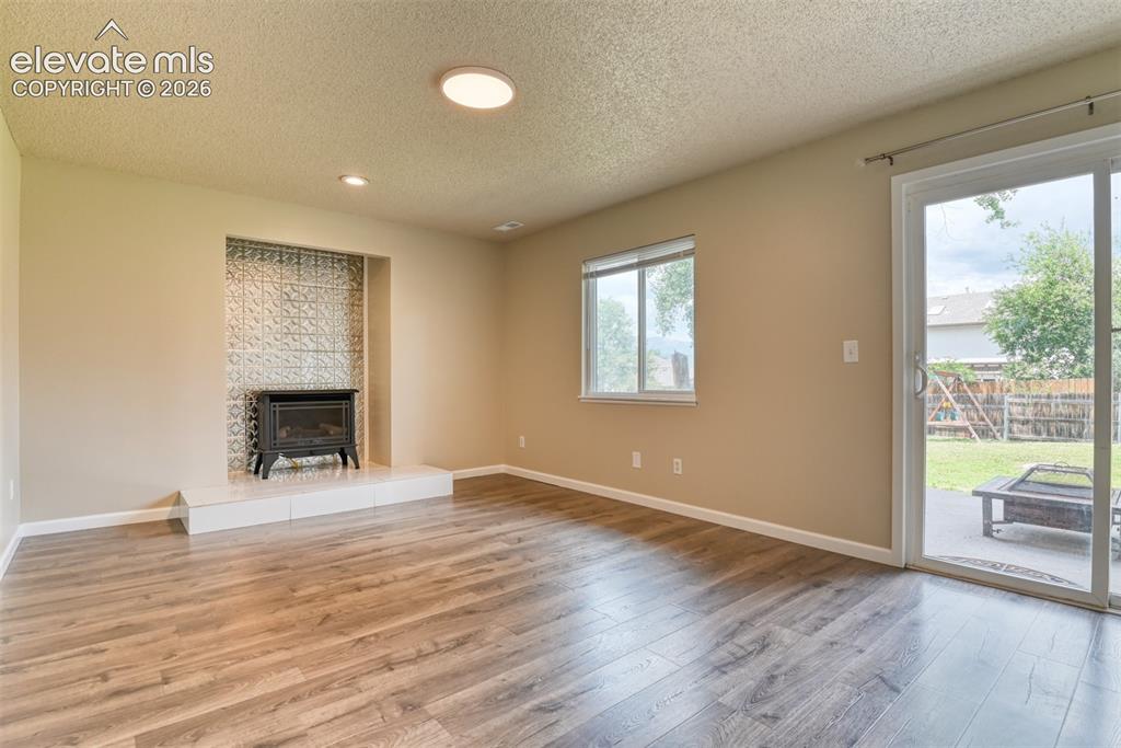 Image 17 of 50: Spacious room with wood-finish flooring, a built-in fireplace with a decora