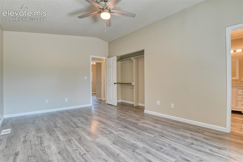 Image 20 of 50: Spacious room featuring wood-finish flooring, neutral-toned walls, and a ce