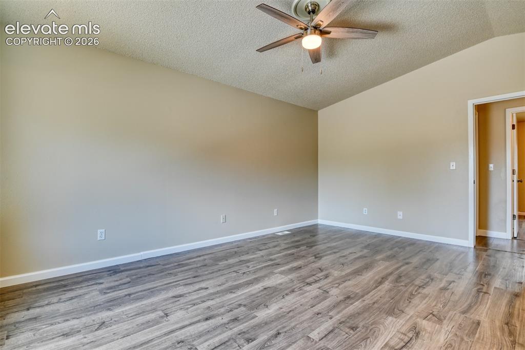 Image 21 of 50: Spacious room featuring wood-finish flooring and neutral wall tones