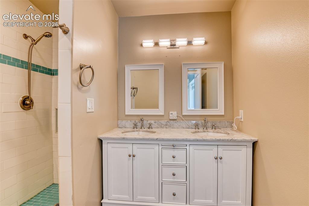 Image 22 of 50: Dual vanity with white cabinetry, granite-finish countertop, and undermount