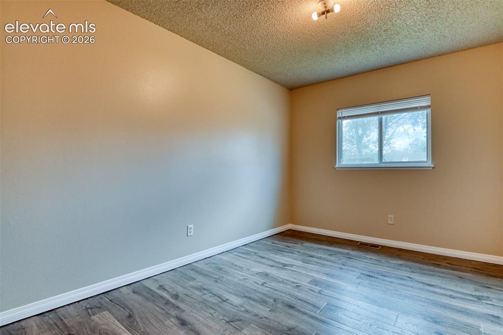 Image 24 of 50: Room featuring wood-finish flooring, neutral wall paint, and a window with