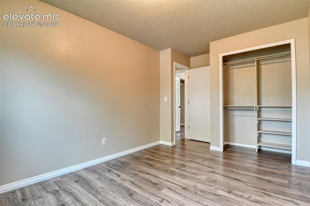 Image 27 of 50: Spacious room featuring wood-finish flooring, neutral-toned walls, white tr