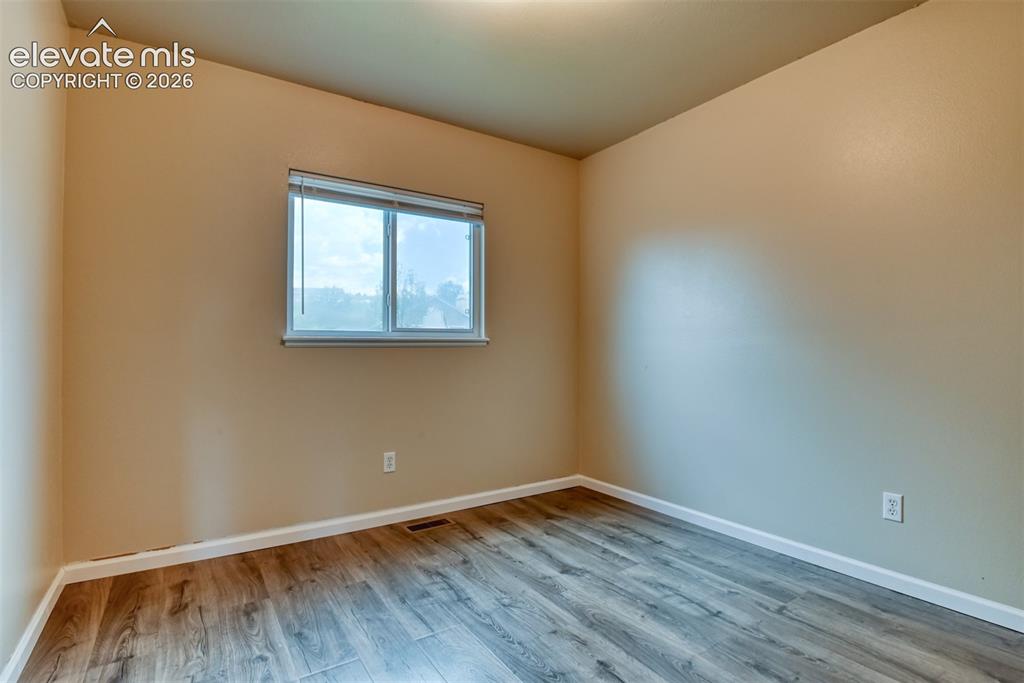 Image 28 of 50: Interior room featuring wood-finish flooring, light-toned walls, and a wind