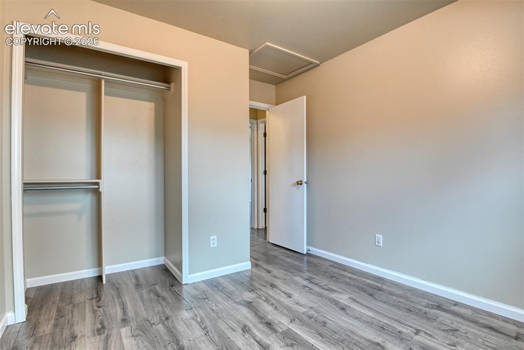 Image 30 of 50: Neutral-toned room featuring wood-finish flooring, a white interior door wi