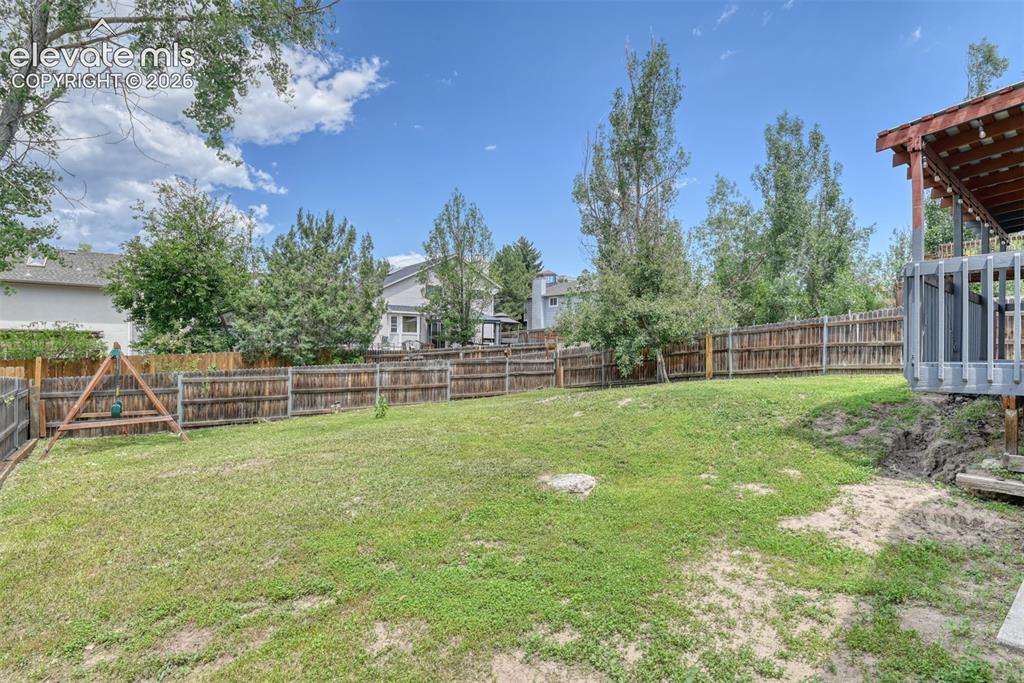 Image 45 of 50: Expansive backyard featuring a partial wood fence, mature trees, and a wood