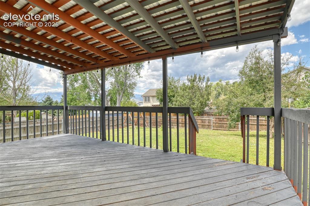 Image 47 of 50: Expansive covered deck featuring wood-finish flooring and a slatted wood ce