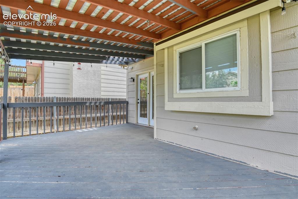 Image 48 of 50: Covered deck featuring a slatted wood ceiling, painted wood railing, wood-f