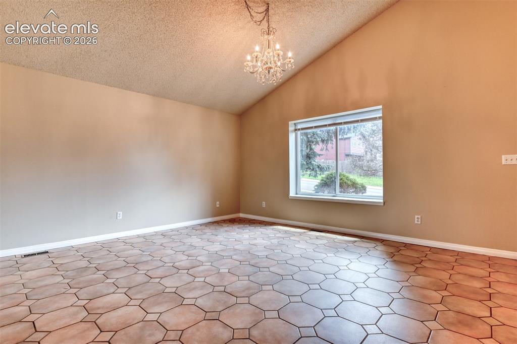 Image 5 of 50: Spacious Living room featuring vaulted ceilings, a prominent window, and ge