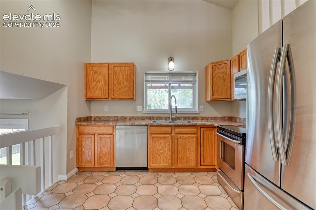 Image 9 of 50: Kitchen featuring wood cabinetry, stainless steel appliances, a double basi