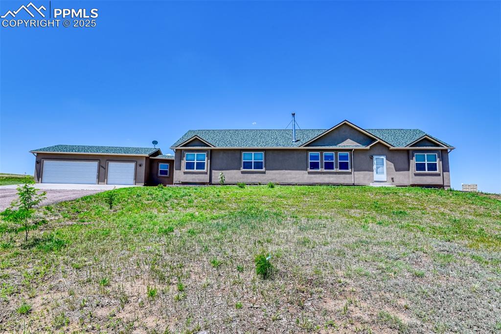 Caption: Ranch-style home with asphalt driveway, stucco siding, a garage, and a front yard