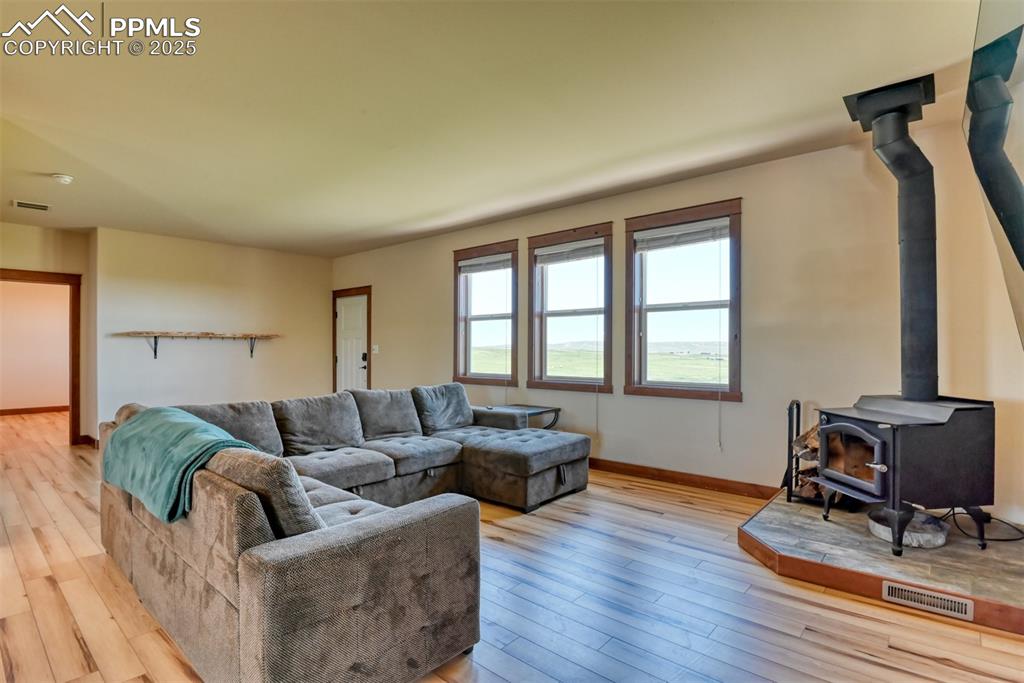 Image 12 of 47: Living room featuring a wood stove and light wood-style floors