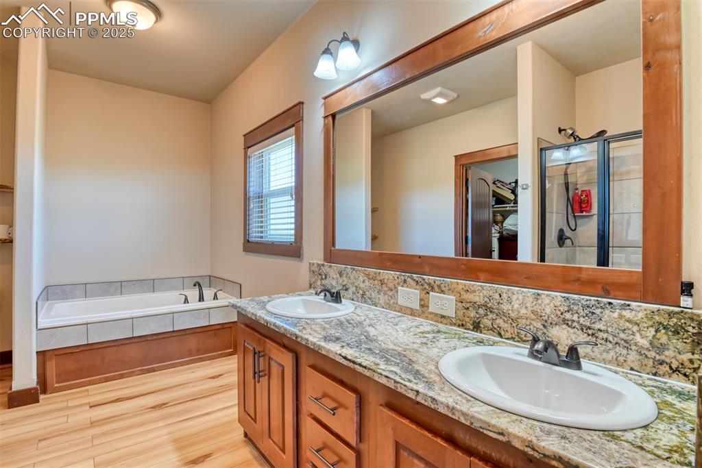 Image 16 of 47: Full bath with LVT wood style flooring, a garden tub, and double vanity