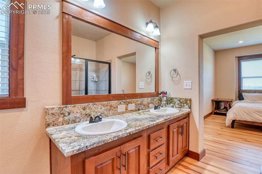 Image 17 of 47: Ensuite bathroom featuring double vanity, wood finished floors, and a stall