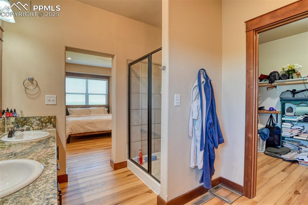 Image 18 of 47: Full bath featuring LVT wood style flooring, a stall shower, double vanity,