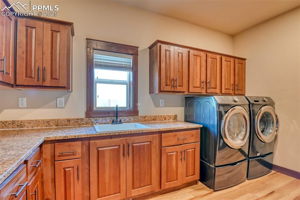 Image 23 of 47: Washroom featuring cabinet space, washer and clothes dryer, and LVT wood st