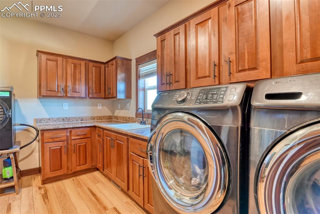 Image 24 of 47: Washroom with washer and dryer, cabinet space, and LVT wood style flooring
