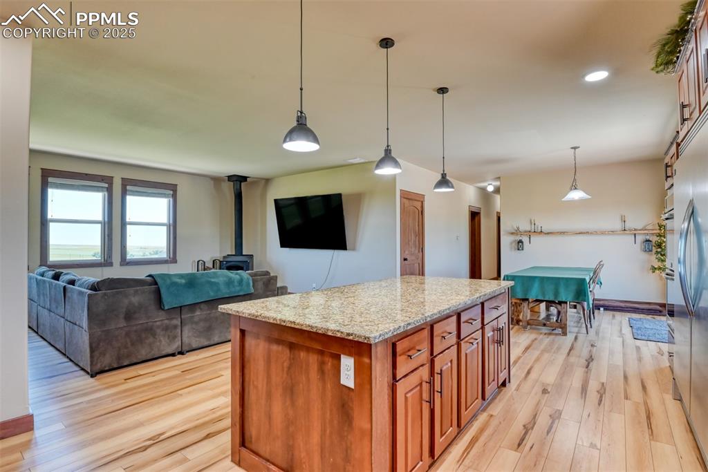Image 7 of 47: Kitchen with a wood stove, light wood-style floors, light stone counters, a