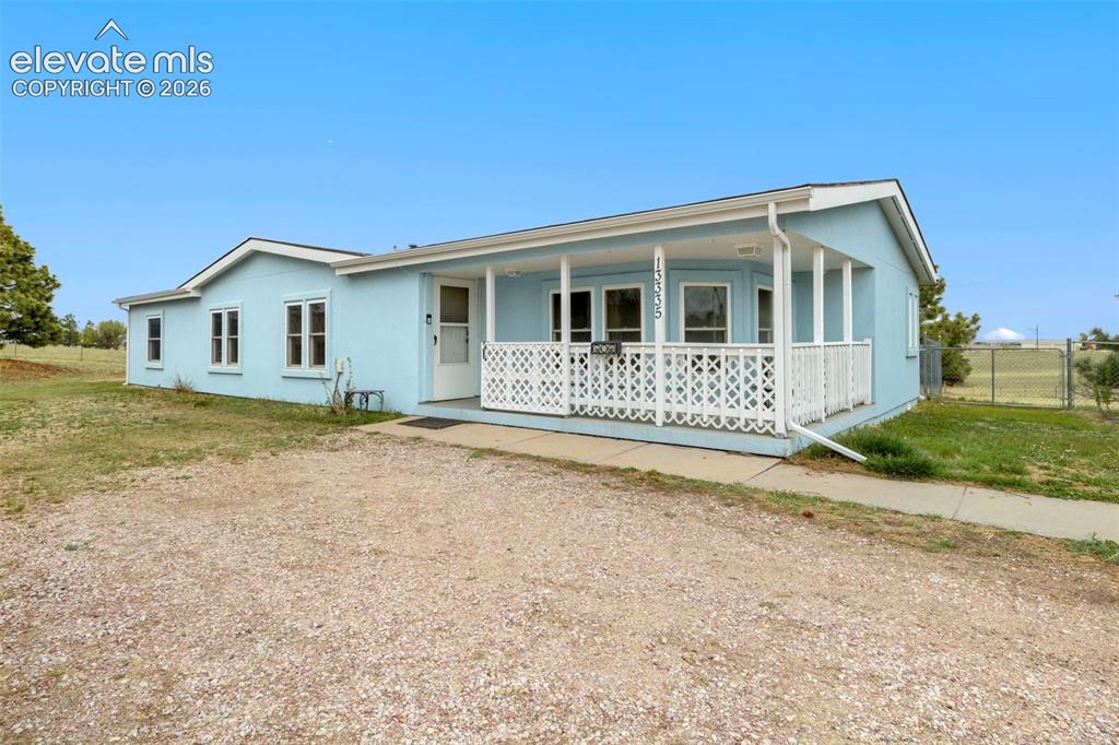 Image 2 of 38: Light blue exterior with a covered front porch featuring white lattice rail