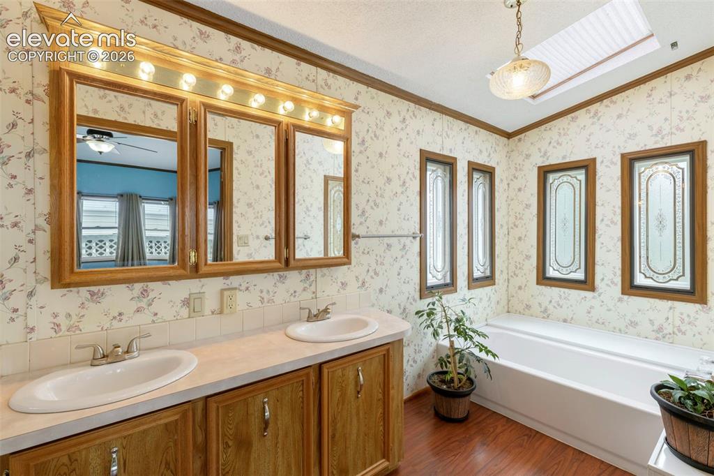 Image 20 of 38: Bathroom featuring a double vanity with wood-finish cabinetry and overhead