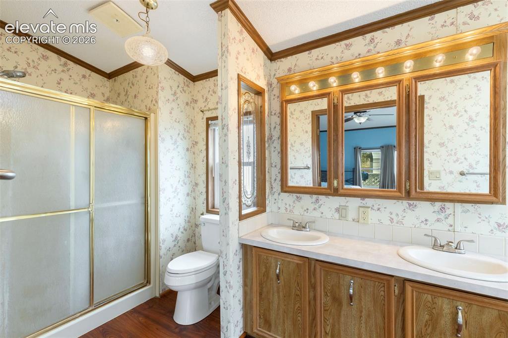 Image 21 of 38: Bathroom featuring a dual vanity with oak-finish cabinetry, a shower with a
