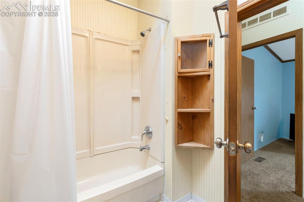Image 31 of 38: Bathtub with integrated shower surround and chrome fixtures