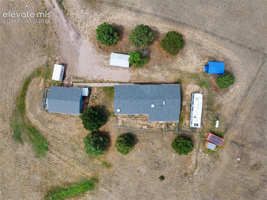 Image 31 of 38: Expansive acreage featuring a main residence with a gray shingle roof, a de